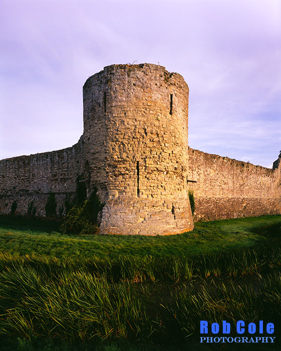 A corner tower of Pevensey Castle in evening light