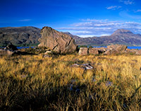 A massive erratic boulder lies on the banks of Loch Maree