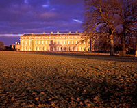 Petworth House illuminated by low winter sun with a heavy brooding sky